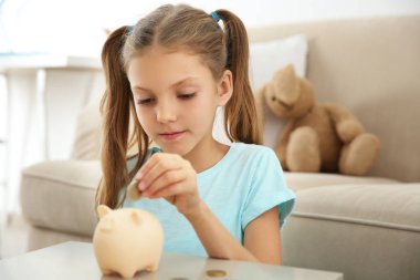 Sevimli kız evde piggy banka para koyarak