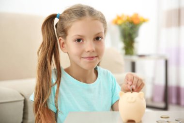 Sevimli kız evde piggy banka para koyarak