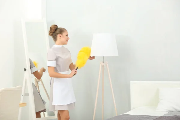 Zimmermädchen putzt Lampe aus Staub — Stockfoto