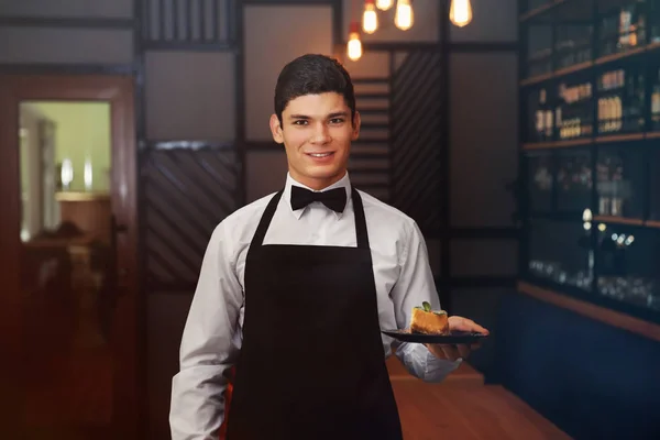 Waiter holding plate with cake — Stock Photo, Image