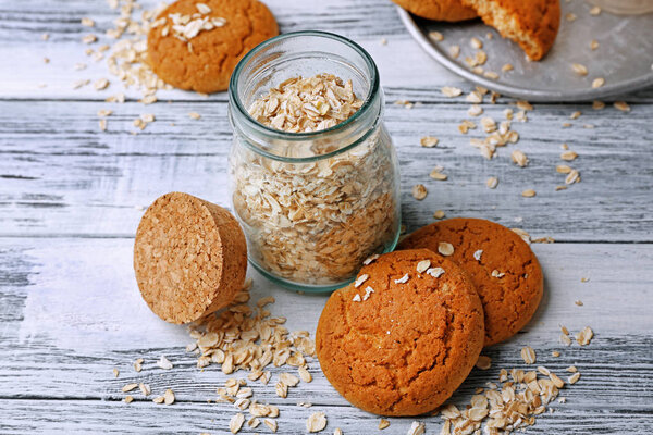 Oatmeal cookies and glass jar with groats