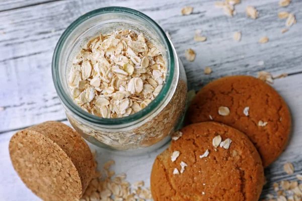 Oatmeal cookies and glass jar with groats — Stock Photo, Image
