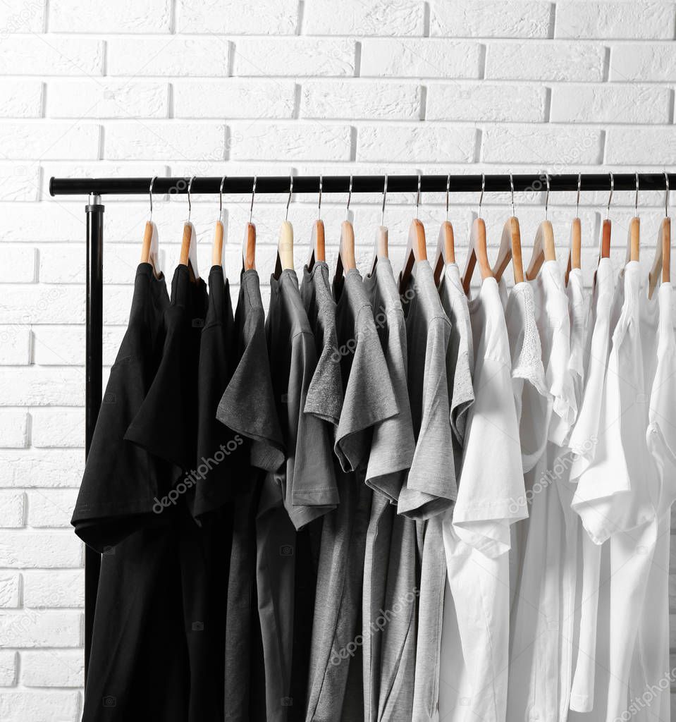 t-shirts on hangers against brick wall