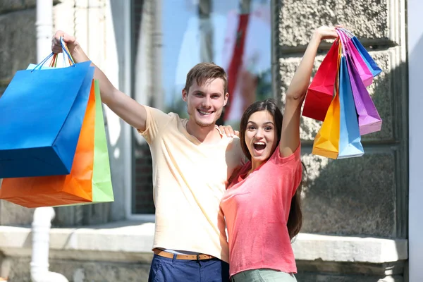 Casal carregando sacos coloridos — Fotografia de Stock