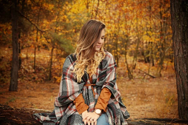 秋の公園で木材のログの上に座って美しい若い女性 — ストック写真