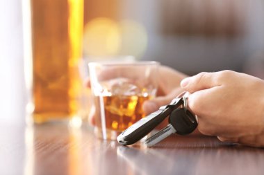 Man sitting in bar with alcoholic beverage and car key, closeup. Don't drink and drive concept clipart