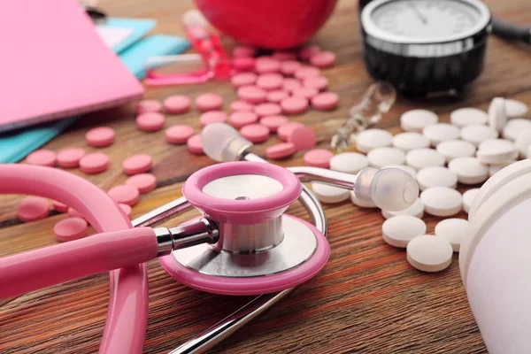 Estetoscópio rosa, comprimidos e outros equipamentos médicos — Fotografia de Stock