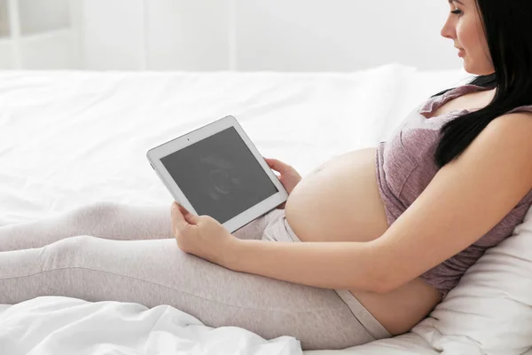 Těhotné ženy při pohledu na tabletu — Stock fotografie