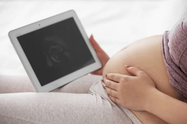 Těhotné ženy při pohledu na tabletu — Stock fotografie