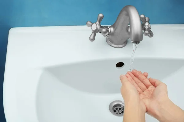 Nuori nainen pesee kädet pesualtaassa — kuvapankkivalokuva