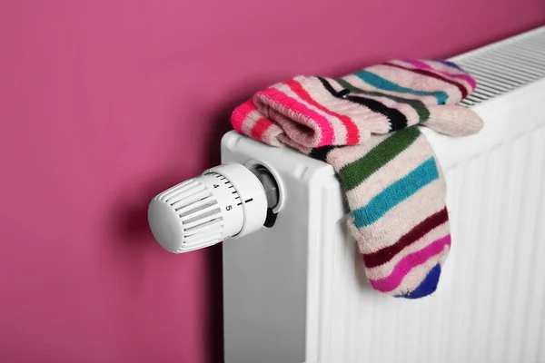 暖针织手套烘干粉红色墙上的暖气散热器背景 — 图库照片