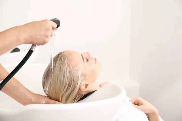 Hairdresser washing woman's hair — Stock Photo, Image