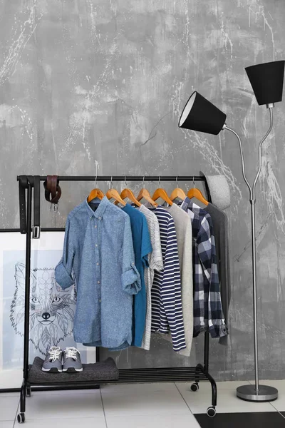 Випадкові стильні чоловічі сорочки на вішалці стоять в кімнаті — стокове фото