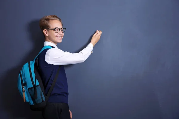 Alumno con mochila de pie cerca de pizarra escolar — Foto de Stock