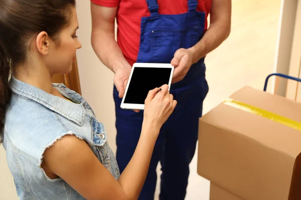 Young woman appending signature after receiving parcel from courier at home