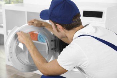 Tesisatçı çamaşır makinesini tamir ediyor.