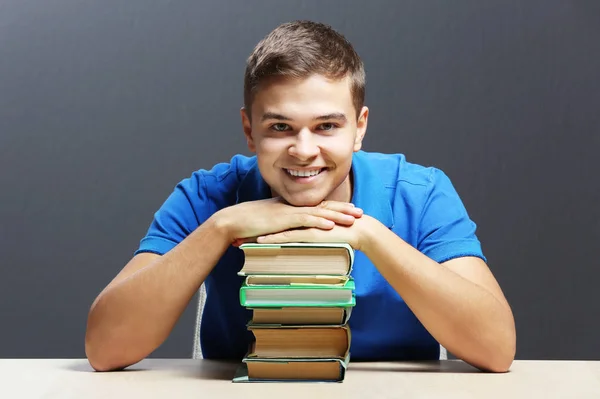 Студент с книгами, сидящий за столом — стоковое фото