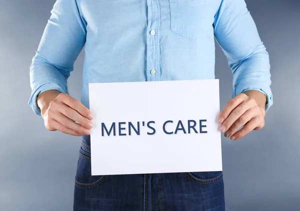 Man holding paper with text MEN'S CARE — Stock Photo, Image