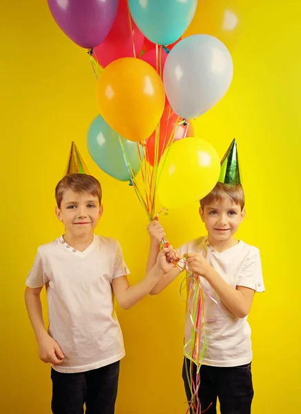 可爱的生日男孩与五颜六色的气球在黄色背景 — 图库照片