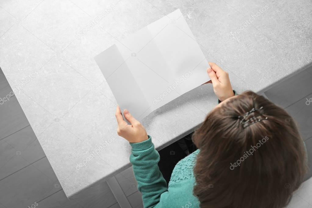 Woman sitting at table with blank booklet