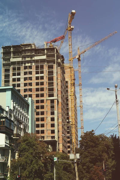 Edifícios e guindastes no céu azul — Fotografia de Stock