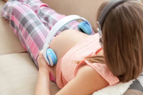 Mujer embarazada sosteniendo auriculares —  Fotos de Stock