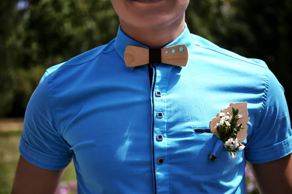 Best man in turquoise shirt with stylish wooden bow tie, close up