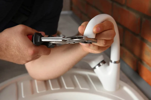 Plumber replacing faucet in kitchen — Stock Photo, Image