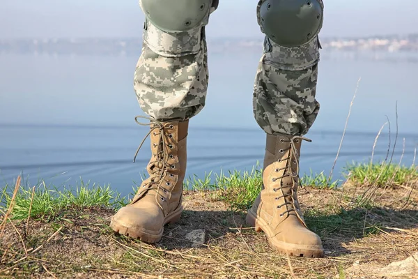 Gambe di soldato in piedi vicino al fiume — Foto Stock