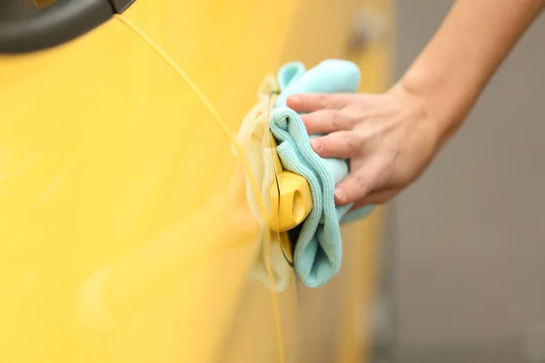 Weibliche Hand reinigt gelbes Auto — Stockfoto