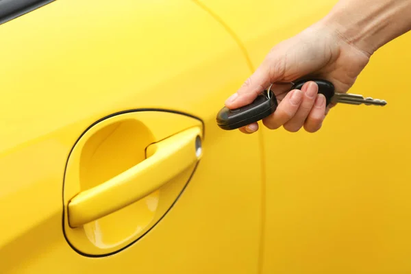 Zbliżenie dłoni kobiece otwarcie żółty samochód — Zdjęcie stockowe
