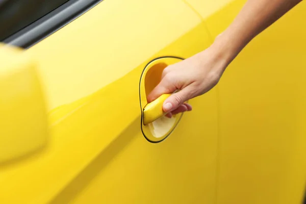 Closeup of female hand opening yellow car — Stock Photo, Image