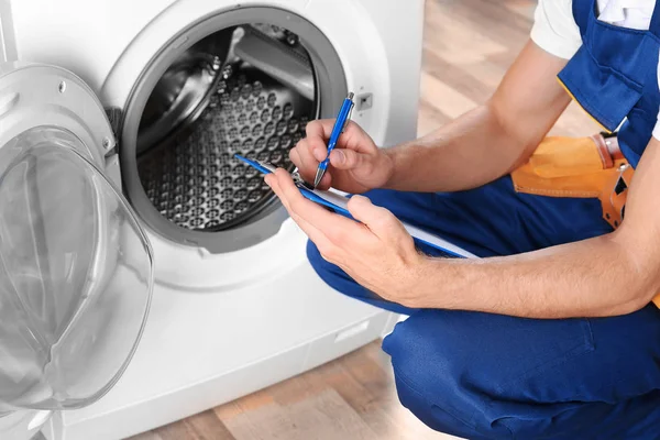 Loodgieter met klembord bij wasmachine — Stockfoto