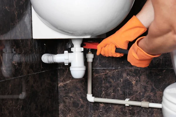 Plumber repairing sink pipe in bathroom