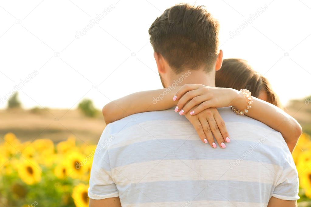 Young man standing back and girl hugging his neck