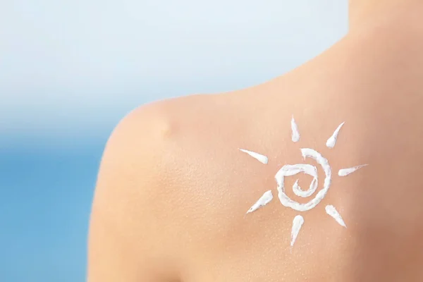 Woman with sun protective lotion in sun shape on shoulder