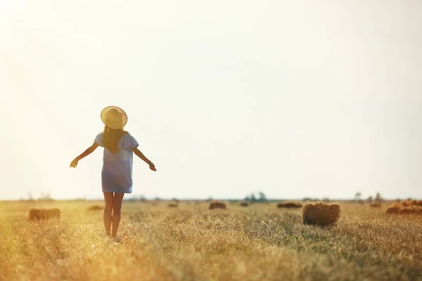 Jonge vrouw in veld op de blauwe hemelachtergrond — Stockfoto