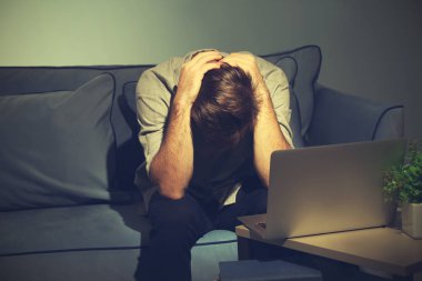 Akşamları evde laptop ile çalışan yorgun genç adam