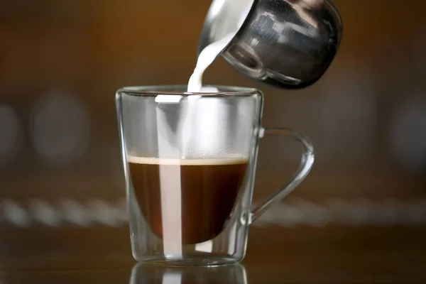 Pouring milk in cup of coffee — Stock Photo, Image