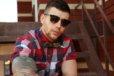 Genç dövmeli adam merdivenlerde, açık poz