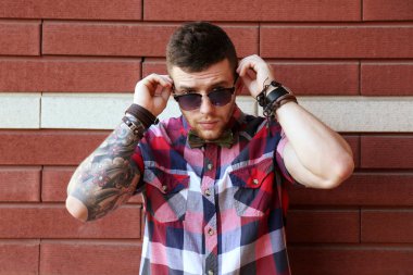 Genç dövmeli adam tuğla duvar arka plan üzerinde poz