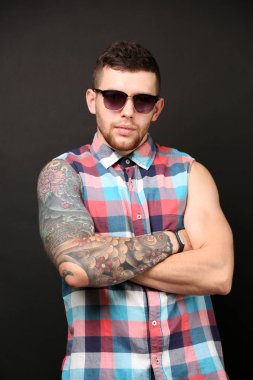 Koyu arka plan üzerinde poz genç dövmeli adam