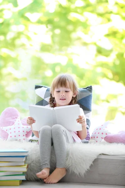 Linda niña leyendo libro en alféizar de ventana —  Fotos de Stock