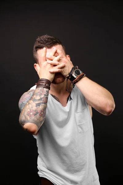 Giovane uomo tatuato posa su sfondo scuro — Foto Stock