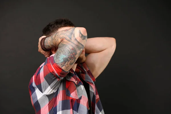 Young tattooed man posing on dark background — Stock Photo, Image