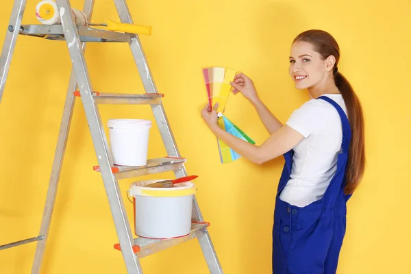 Bella giovane decoratore selezionando il colore della parete, su sfondo giallo — Foto Stock