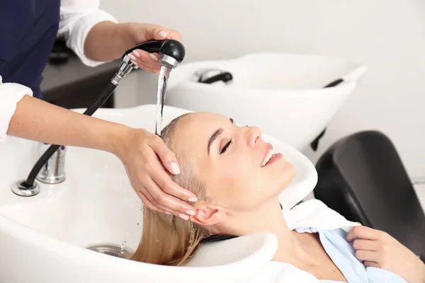 Hairdresser washing woman's hair — Stock Photo, Image