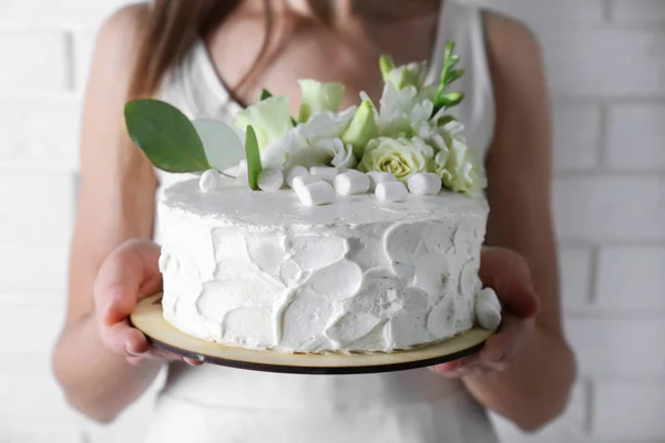 Woman holding cake with marshmallows and flowers — Stock Photo, Image