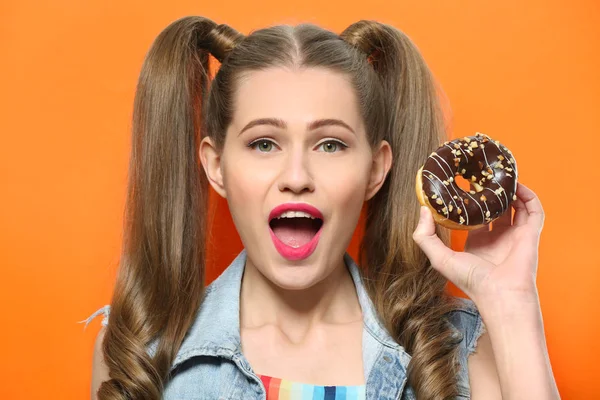 Rolig ung kvinna med välsmakande donut på orange bakgrund, närbild — Stockfoto