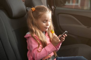 Küçük bir arabanın içinde smartphone kullanarak lolipop kızla